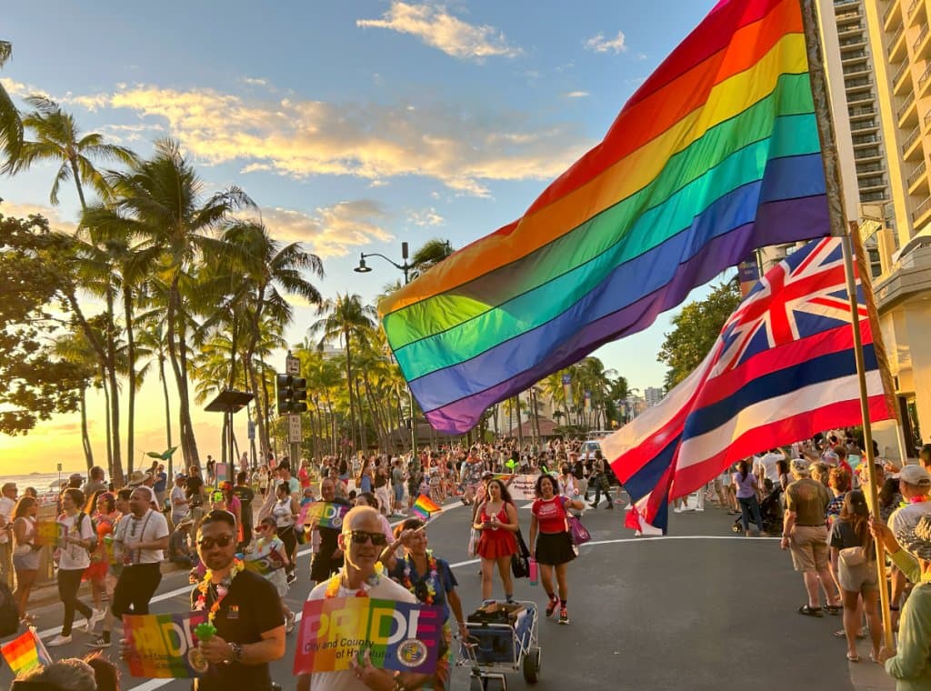 Honolulu Pride parade with rainbow and Hawaiian flags
